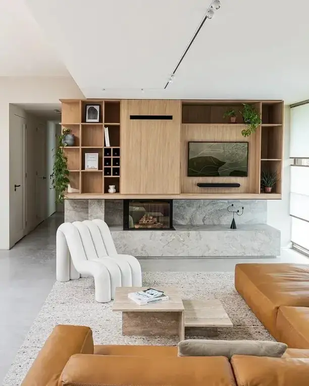 Een plafondrail met spots boven een woonkamer met een houten wandkast en een haard