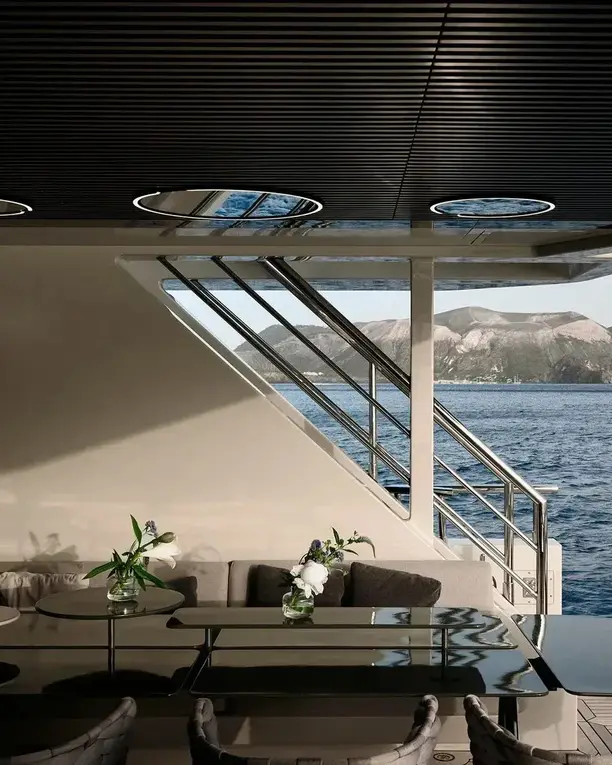 Een lounge met ingebouwde lichtringen in een donker plafond en een open zicht op zee