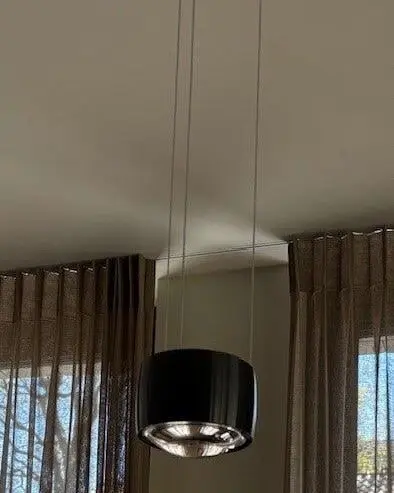 Een zwarte hanglamp voor lange taupe vitrages