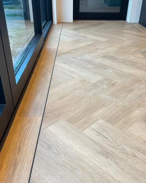 De visgraatvloer met bies langs een pui met zwarte kozijnen