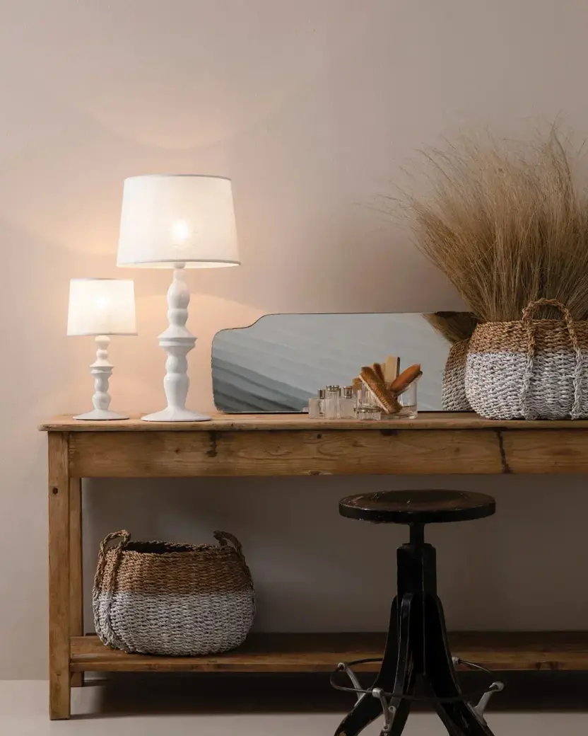 Twee witte keramieken tafellampen op een oude eiken wandtafel met manden en gedroogd gras