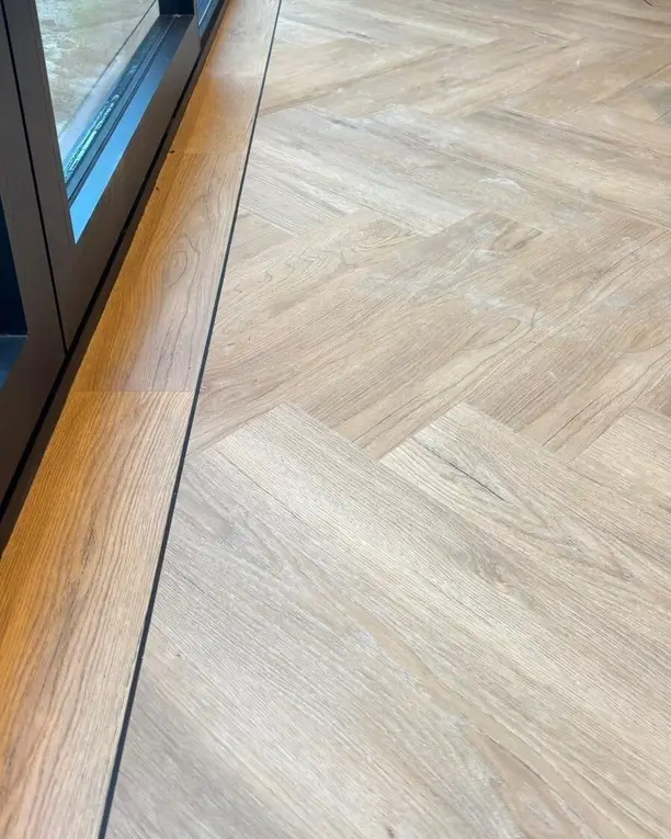 De visgraatvloer met bies langs een glazen schuifpui