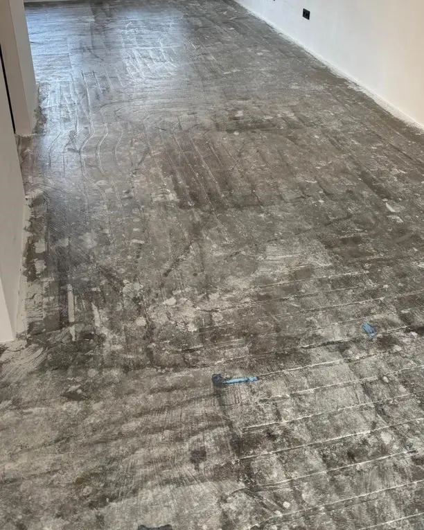 Een lege kamer met een kale betonvloer vol lijmresten